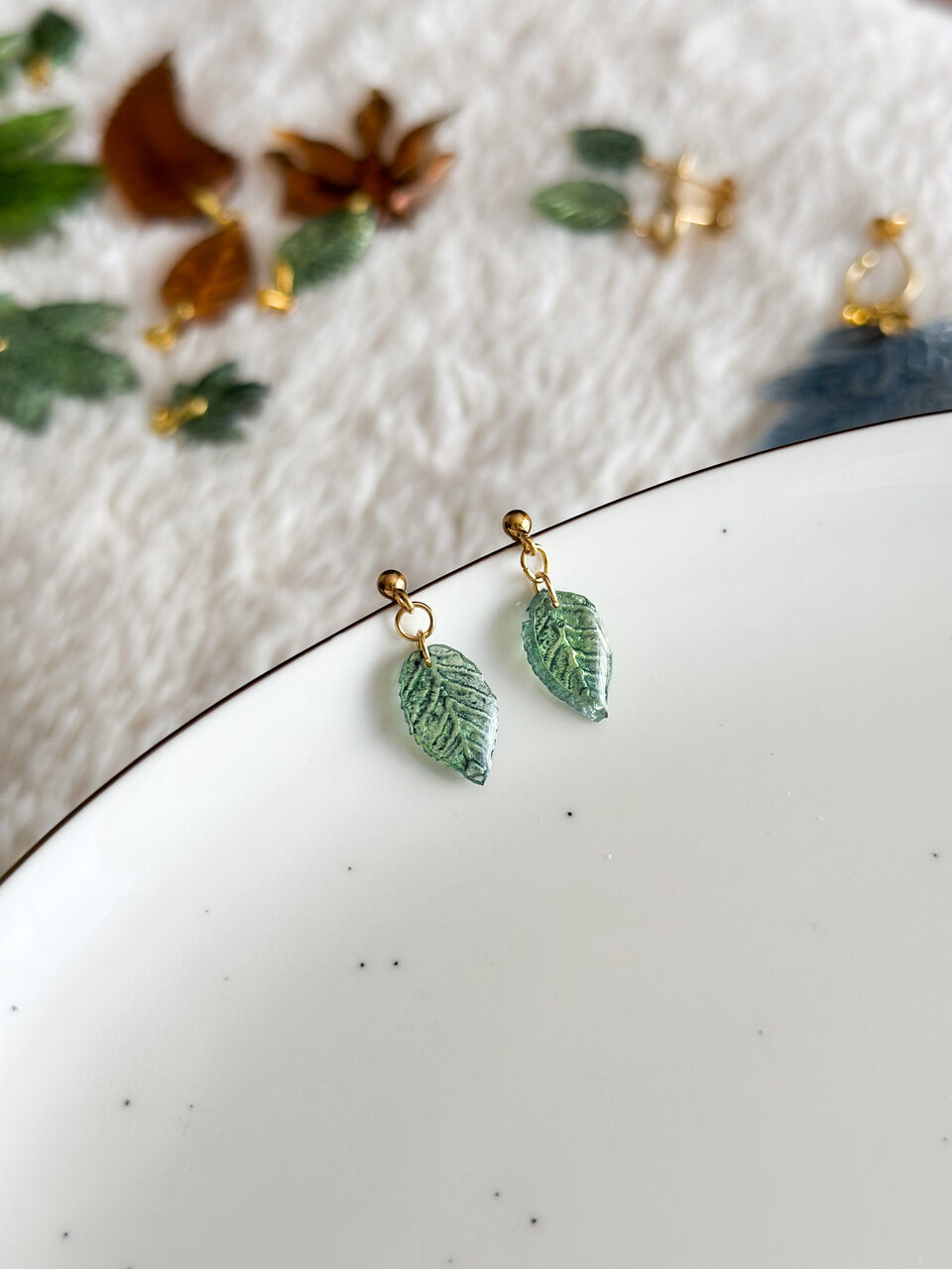 kolczyki zielone liście, ręcznie malowane kolczyki, biżuteria handmade, kolczyki z żywicy, artystyczna biżuteria, kolczyki liście, lekkie kolczyki, kolczyki złote, kolczyki na prezent, unikalna biżuteria, kolczyki dwustronne, kolczyki handmade, kolczyki inspirowane naturą, eleganckie kolczyki, kolczyki z żywicy epoksydowej