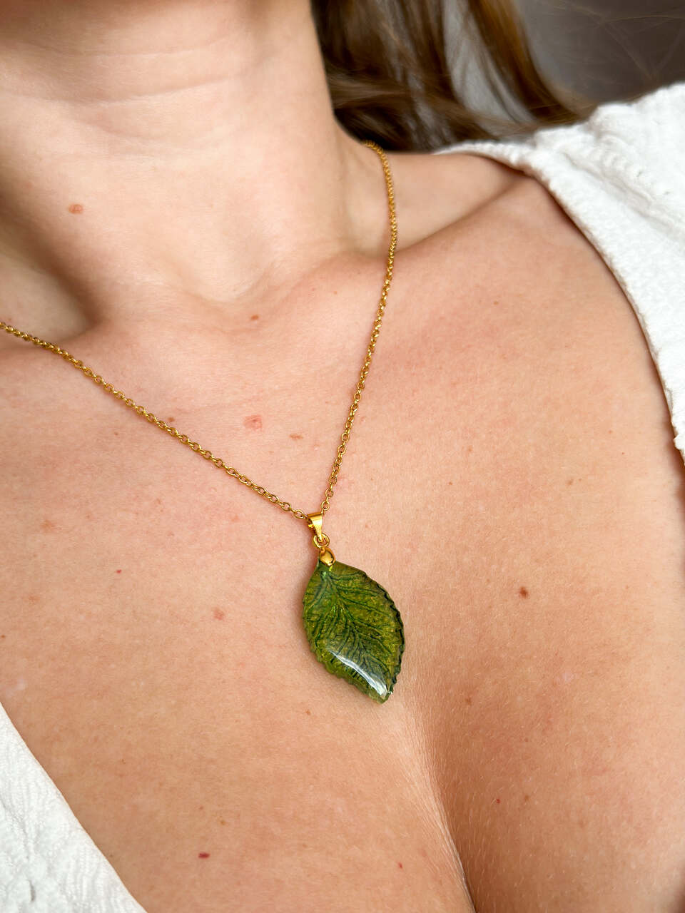 Ręcznie malowany naszyjnik w kształcie zielonego liścia – delikatny, mieniący się i lekki. Unikalna biżuteria handmade inspirowana naturą.