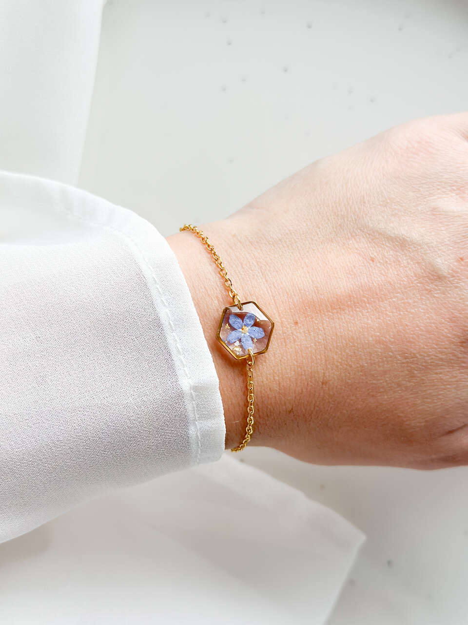 bransoletka z niezapominajką, bransoletka z sześcianem z żywicy, złota bransoletka z żywicy, biżuteria z kwiatami, bransoletka handmade, bransoletka z żywicy epoksydowej, delikatna bransoletka damska, naturalna biżuteria z kwiatów, bransoletka z niezapominajką w żywicy, prezent dla niej, biżuteria z niezapominajką