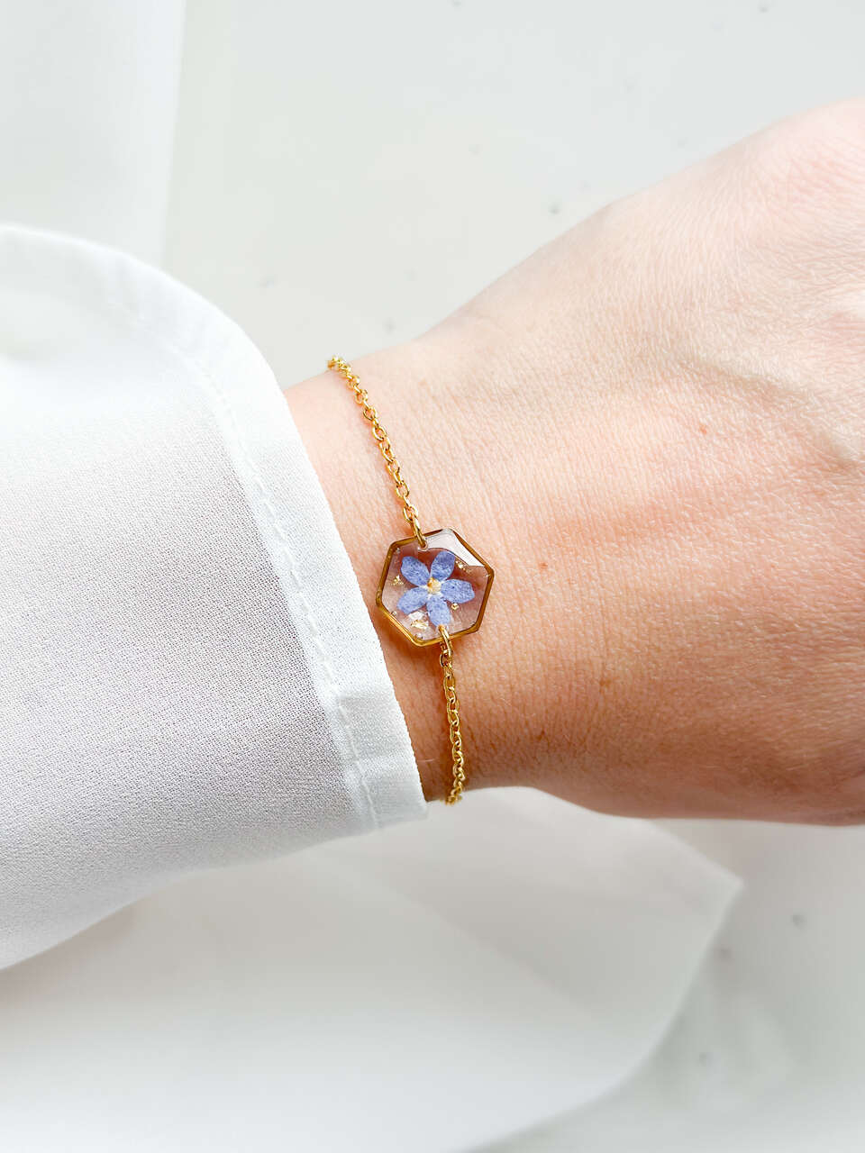 bransoletka z niezapominajką, bransoletka z sześcianem z żywicy, złota bransoletka z żywicy, biżuteria z kwiatami, bransoletka handmade, bransoletka z żywicy epoksydowej, delikatna bransoletka damska, naturalna biżuteria z kwiatów, bransoletka z niezapominajką w żywicy, prezent dla niej, biżuteria z niezapominajką