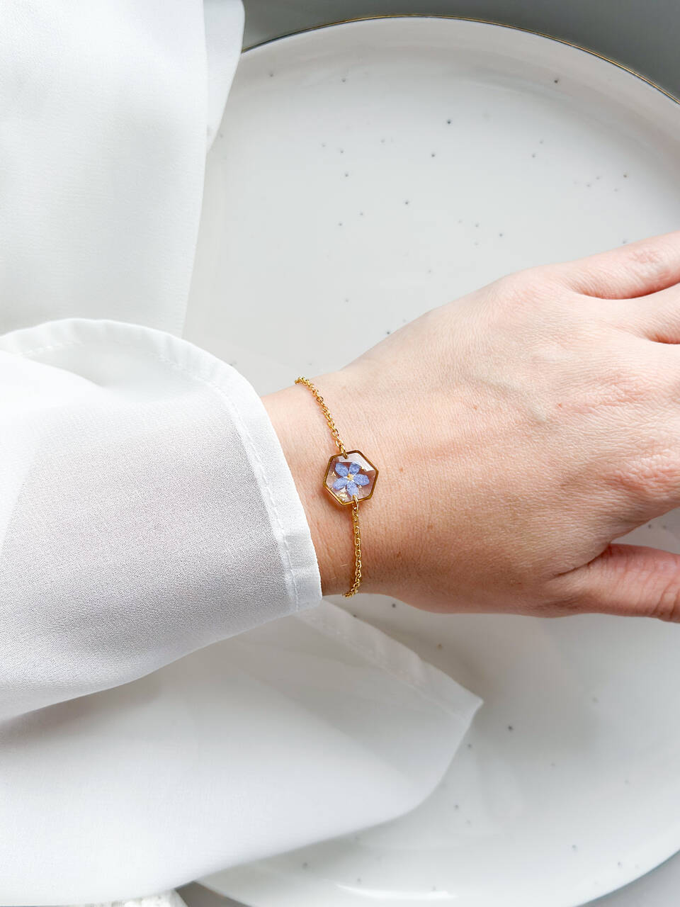 bransoletka z niezapominajką, bransoletka z sześcianem z żywicy, złota bransoletka z żywicy, biżuteria z kwiatami, bransoletka handmade, bransoletka z żywicy epoksydowej, delikatna bransoletka damska, naturalna biżuteria z kwiatów, bransoletka z niezapominajką w żywicy, prezent dla niej, biżuteria z niezapominajką