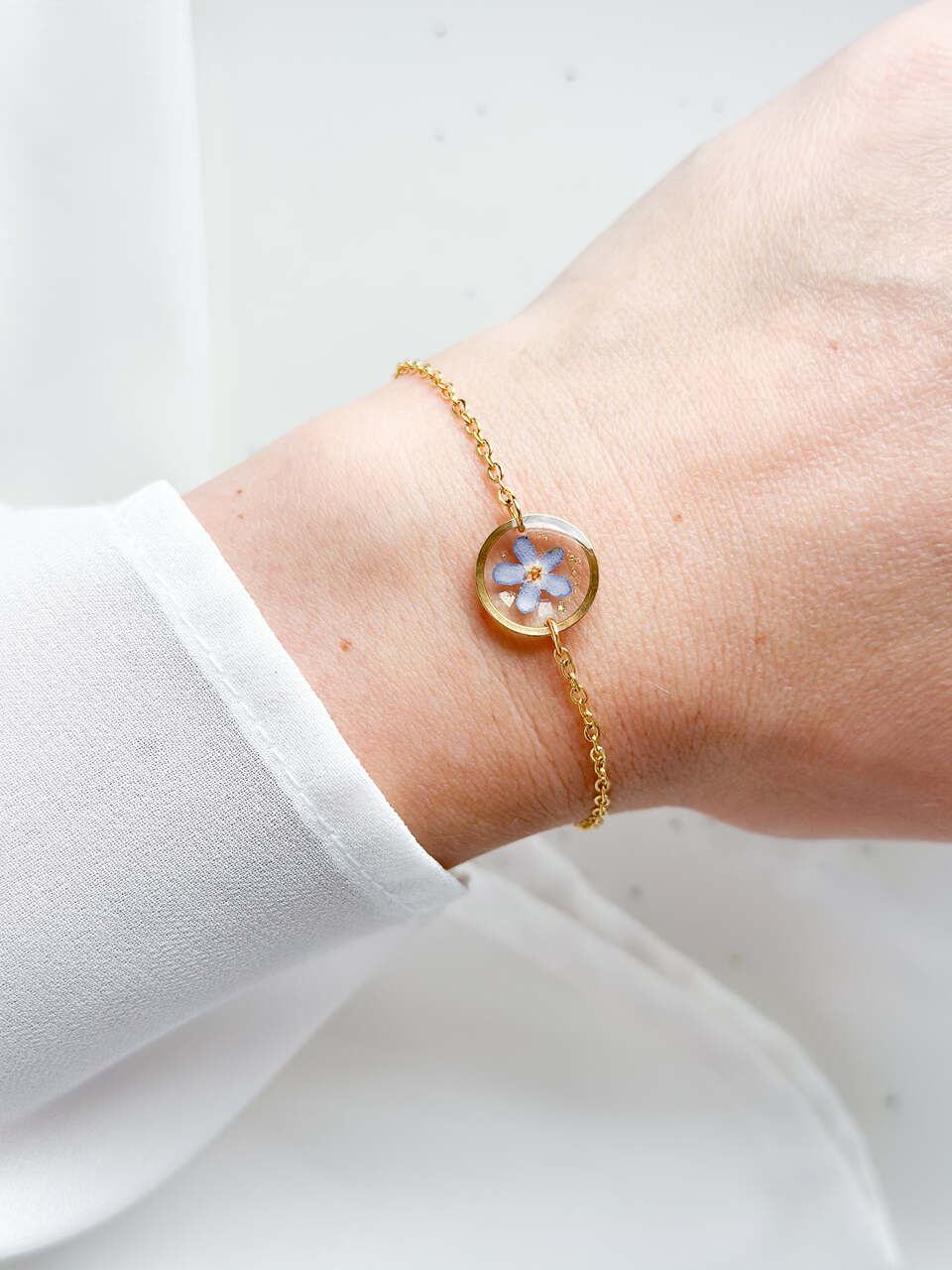 bransoletka z niezapominajką, złota bransoletka z żywicy, bransoletka z kwiatem w żywicy, biżuteria z niezapominajką, delikatna bransoletka handmade, naturalna biżuteria z kwiatów, bransoletka z żywicy epoksydowej, bransoletka z kwiatami, prezent dla niej, złota biżuteria z żywicy