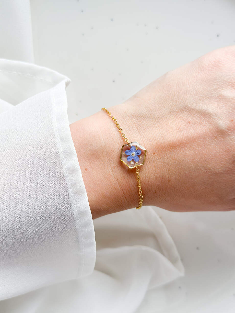 bransoletka z niezapominajką, bransoletka z sześcianem z żywicy, złota bransoletka z żywicy, biżuteria z kwiatami, bransoletka handmade, bransoletka z żywicy epoksydowej, delikatna bransoletka damska, naturalna biżuteria z kwiatów, bransoletka z niezapominajką w żywicy, prezent dla niej, biżuteria z niezapominajką