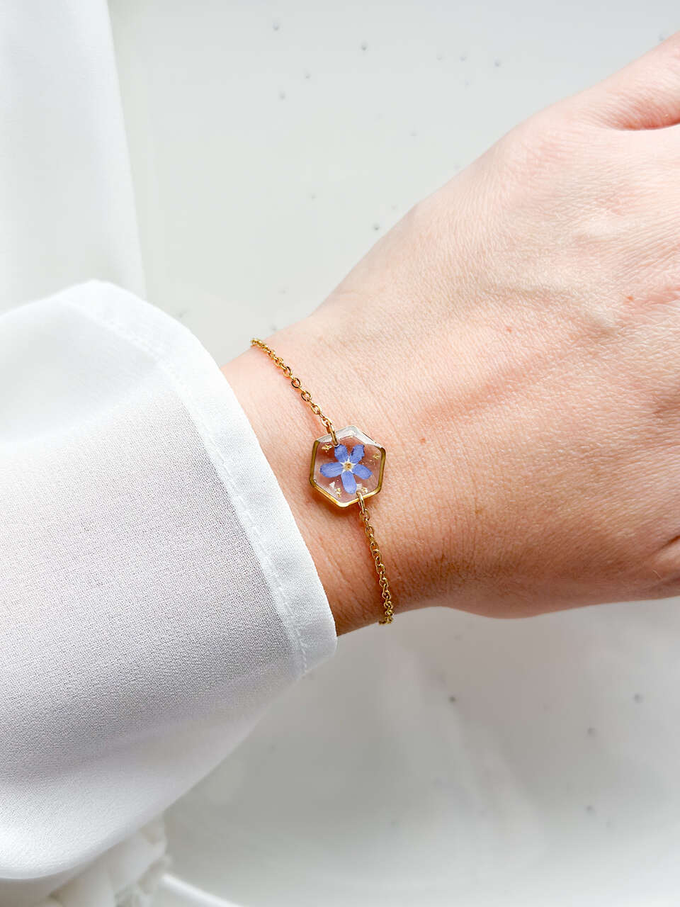 bransoletka z niezapominajką, bransoletka z sześcianem z żywicy, złota bransoletka z żywicy, biżuteria z kwiatami, bransoletka handmade, bransoletka z żywicy epoksydowej, delikatna bransoletka damska, naturalna biżuteria z kwiatów, bransoletka z niezapominajką w żywicy, prezent dla niej, biżuteria z niezapominajką