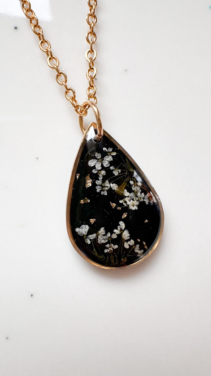 naszyjnik z prawdziwych kwiatów zalanych żywicą epoksydową, biżuteria z suszonymi kwiatami, ręcznie robiony naszyjnik z suszonych kwiatów, biżuteria z żywicy epoksydowej i suszonych kwiatów, biżuteria z kwiatami zalanymi żywicą, kwiaty w żywicy epoksydowej, pomysł na prezent, złoty naszyjnik łezka, naszyjnik z czarnym tłem, biżuteria handmade, naturalna biżuteria