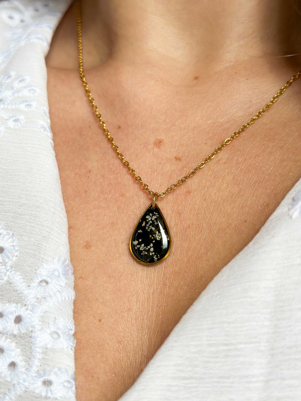 naszyjnik z prawdziwych kwiatów zalanych żywicą epoksydową, biżuteria z suszonymi kwiatami, ręcznie robiony naszyjnik z suszonych kwiatów, biżuteria z żywicy epoksydowej i suszonych kwiatów, biżuteria z kwiatami zalanymi żywicą, kwiaty w żywicy epoksydowej, pomysł na prezent, złoty naszyjnik łezka, naszyjnik z czarnym tłem, biżuteria handmade, naturalna biżuteria