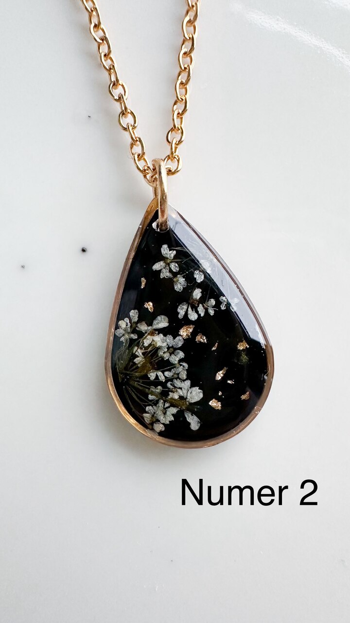 naszyjnik z prawdziwych kwiatów zalanych żywicą epoksydową, biżuteria z suszonymi kwiatami, ręcznie robiony naszyjnik z suszonych kwiatów, biżuteria z żywicy epoksydowej i suszonych kwiatów, biżuteria z kwiatami zalanymi żywicą, kwiaty w żywicy epoksydowej, pomysł na prezent, złoty naszyjnik łezka, naszyjnik z czarnym tłem, biżuteria handmade, naturalna biżuteria