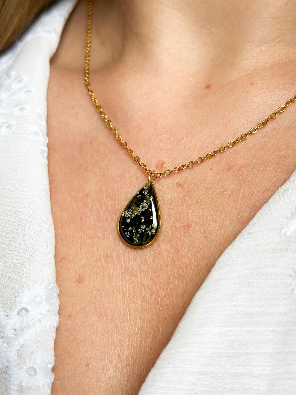 naszyjnik z prawdziwych kwiatów zalanych żywicą epoksydową, biżuteria z suszonymi kwiatami, ręcznie robiony naszyjnik z suszonych kwiatów, biżuteria z żywicy epoksydowej i suszonych kwiatów, biżuteria z kwiatami zalanymi żywicą, kwiaty w żywicy epoksydowej, pomysł na prezent, złoty naszyjnik łezka, naszyjnik z czarnym tłem, biżuteria handmade, naturalna biżuteria