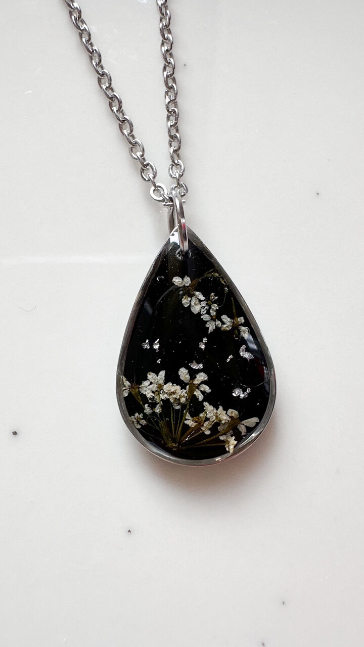 naszyjnik z prawdziwych kwiatów zalanych żywicą epoksydową, biżuteria z suszonymi kwiatami, ręcznie robiony naszyjnik z suszonych kwiatów, biżuteria z żywicy epoksydowej i suszonych kwiatów, biżuteria z kwiatami zalanymi żywicą, kwiaty w żywicy epoksydowej, pomysł na prezent, srebrny naszyjnik łezka, naszyjnik z czarnym tłem, biżuteria handmade, naturalna biżuteria
