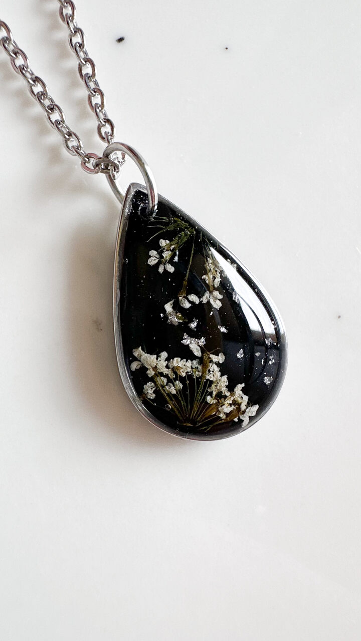 naszyjnik z prawdziwych kwiatów zalanych żywicą epoksydową, biżuteria z suszonymi kwiatami, ręcznie robiony naszyjnik z suszonych kwiatów, biżuteria z żywicy epoksydowej i suszonych kwiatów, biżuteria z kwiatami zalanymi żywicą, kwiaty w żywicy epoksydowej, pomysł na prezent, srebrny naszyjnik łezka, naszyjnik z czarnym tłem, biżuteria handmade, naturalna biżuteria