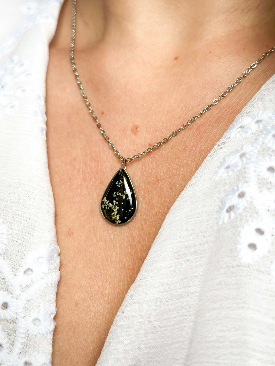 naszyjnik z prawdziwych kwiatów zalanych żywicą epoksydową, biżuteria z suszonymi kwiatami, ręcznie robiony naszyjnik z suszonych kwiatów, biżuteria z żywicy epoksydowej i suszonych kwiatów, biżuteria z kwiatami zalanymi żywicą, kwiaty w żywicy epoksydowej, pomysł na prezent, srebrny naszyjnik łezka, naszyjnik z czarnym tłem, biżuteria handmade, naturalna biżuteria