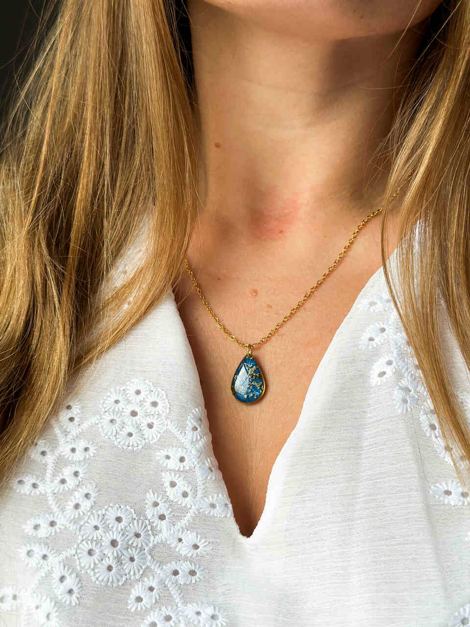 naszyjnik z prawdziwymi kwiatami, naszyjnik z żywicy epoksydowej, biżuteria z suszonymi kwiatami, ręcznie robiony naszyjnik z suszonych kwiatów, biżuteria z kwiatami zalanymi żywicą, kwiaty w żywicy epoksydowej, złoty naszyjnik z żywicy, naszyjnik z kwiatami marchwi zwyczajnej, biżuteria handmade, naszyjnik łezka z żywicy, naszyjnik z niebieskim tłem, elegancki naszyjnik z kwiatami, unikatowa biżuteria z żywicy, pomysł na prezent dla niej, złota biżuteria z kwiatami