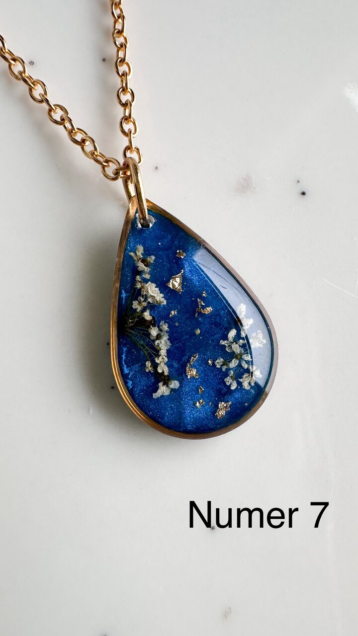 naszyjnik z prawdziwymi kwiatami, naszyjnik z żywicy epoksydowej, biżuteria z suszonymi kwiatami, ręcznie robiony naszyjnik z suszonych kwiatów, biżuteria z kwiatami zalanymi żywicą, kwiaty w żywicy epoksydowej, złoty naszyjnik z żywicy, naszyjnik z kwiatami marchwi zwyczajnej, biżuteria handmade, naszyjnik łezka z żywicy, naszyjnik z niebieskim tłem, elegancki naszyjnik z kwiatami, unikatowa biżuteria z żywicy, pomysł na prezent dla niej, złota biżuteria z kwiatami