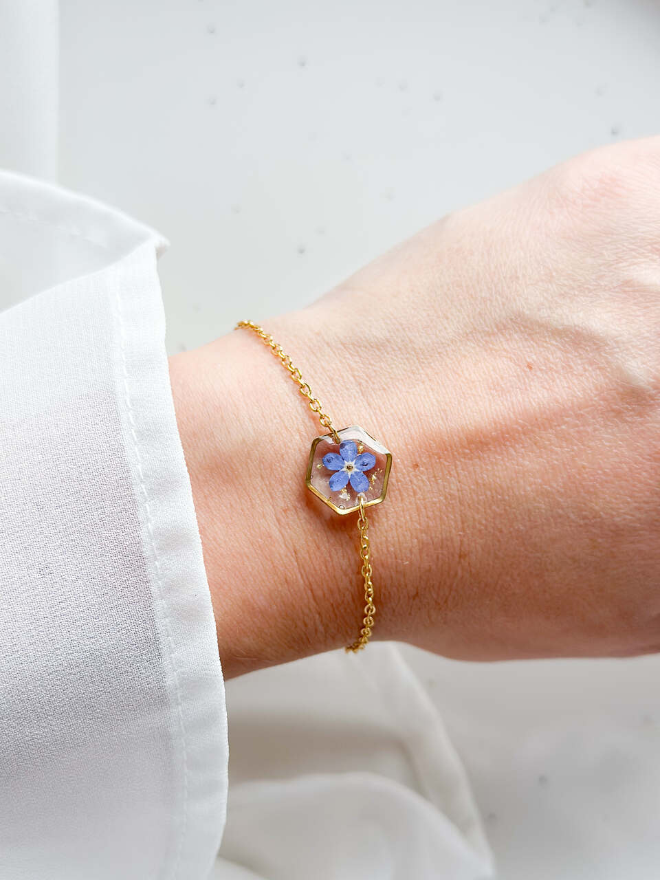 bransoletka z niezapominajką, bransoletka z sześcianem z żywicy, złota bransoletka z żywicy, biżuteria z kwiatami, bransoletka handmade, bransoletka z żywicy epoksydowej, delikatna bransoletka damska, naturalna biżuteria z kwiatów, bransoletka z niezapominajką w żywicy, prezent dla niej, biżuteria z niezapominajką