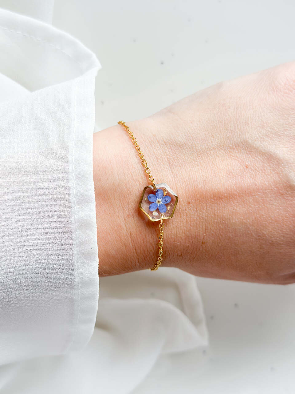 bransoletka z niezapominajką, bransoletka z sześcianem z żywicy, złota bransoletka z żywicy, biżuteria z kwiatami, bransoletka handmade, bransoletka z żywicy epoksydowej, delikatna bransoletka damska, naturalna biżuteria z kwiatów, bransoletka z niezapominajką w żywicy, prezent dla niej, biżuteria z niezapominajką