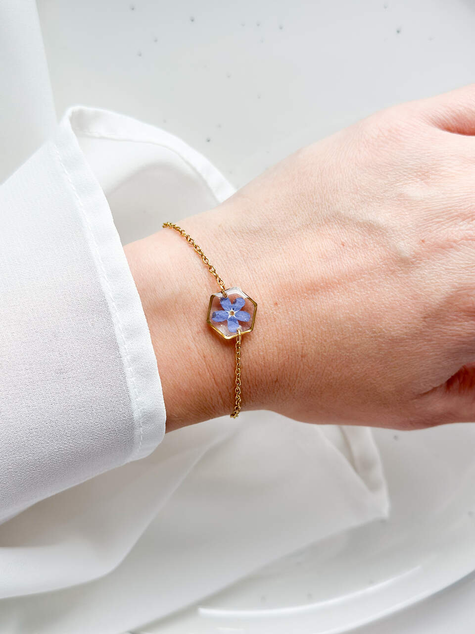 bransoletka z niezapominajką, bransoletka z sześcianem z żywicy, złota bransoletka z żywicy, biżuteria z kwiatami, bransoletka handmade, bransoletka z żywicy epoksydowej, delikatna bransoletka damska, naturalna biżuteria z kwiatów, bransoletka z niezapominajką w żywicy, prezent dla niej, biżuteria z niezapominajką