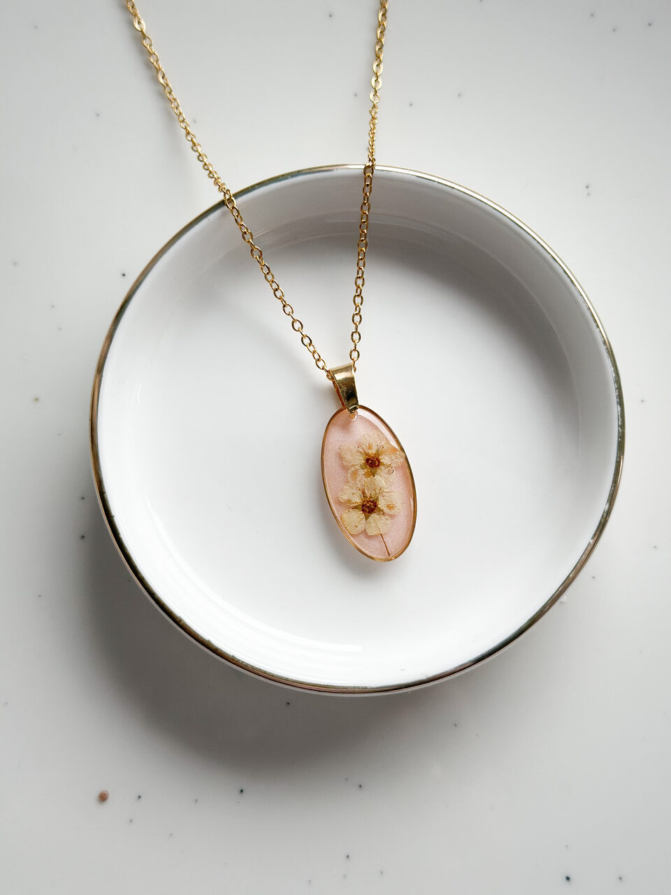 naszyjnik z kwiatów zalanych żywicą, biżuteria z prawdziwych kwiatów, biżuteria z suszonych kwiatów, ręcznie robiona biżuteria z żywicy, złoty naszyjnik elipsa, złoty medalion z kwiatem, biżuteria handmade, naszyjnik z żywicy z kwiatami, biżuteria artystyczna, biżuteria z natury, biżuteria z żywicy epoksydowej, delikatna biżuteria dla niej, oryginalny pomysł na prezent dla niej, unikalny prezent dla kobiety, naszyjnik z prawdziwymi kwiatami, biżuteria z żywicy handmade, kwiaty zatopione w żywicy, biżuteria dla miłośniczki natury