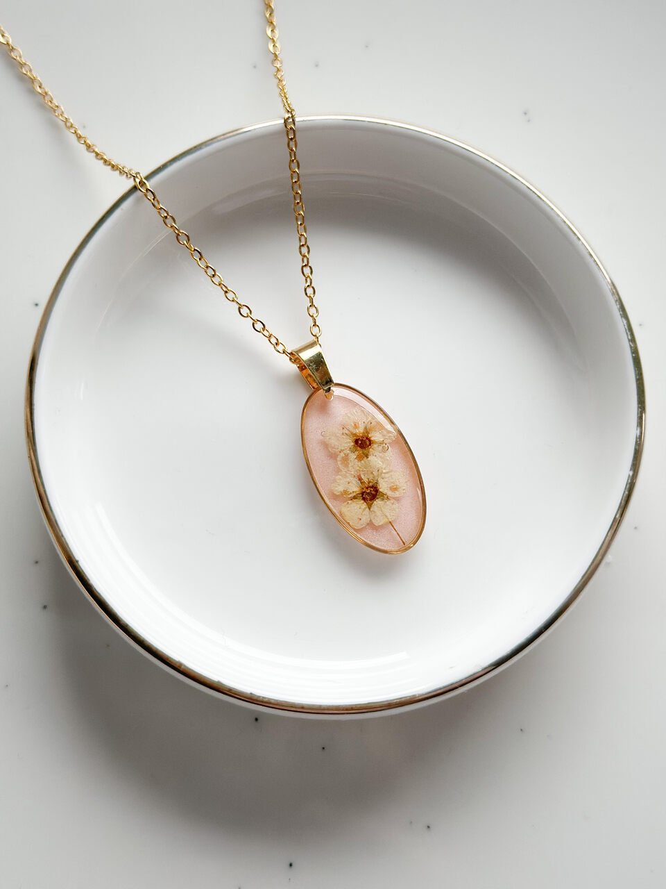 naszyjnik z kwiatów zalanych żywicą, biżuteria z prawdziwych kwiatów, biżuteria z suszonych kwiatów, ręcznie robiona biżuteria z żywicy, złoty naszyjnik elipsa, złoty medalion z kwiatem, biżuteria handmade, naszyjnik z żywicy z kwiatami, biżuteria artystyczna, biżuteria z natury, biżuteria z żywicy epoksydowej, delikatna biżuteria dla niej, oryginalny pomysł na prezent dla niej, unikalny prezent dla kobiety, naszyjnik z prawdziwymi kwiatami, biżuteria z żywicy handmade, kwiaty zatopione w żywicy, biżuteria dla miłośniczki natury