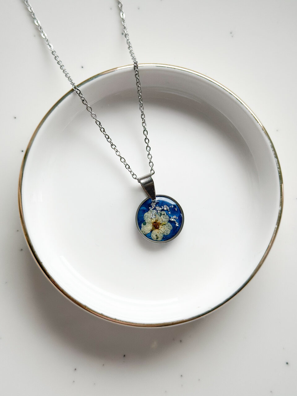 naszyjnik z kwiatów zalanych żywicą, biżuteria z prawdziwych kwiatów, biżuteria z żywicy epoksydowej, naszyjnik z żywicy z kwiatami, ręcznie robiona biżuteria z żywicy, biżuteria z suszonych kwiatów, nietypowy pomysł na prezent dla niej, biżuteria handmade, biżuteria z natury, prezent dla kobiety, unikalny prezent dla niej, naszyjnik z prawdziwymi kwiatami, naszyjnik z niebieskim tłem, naszyjnik szafirowy, biżuteria w kolorze kobaltowym, chabrowy naszyjnik z żywicy, delikatna biżuteria dla niej, ręcznie robiony naszyjnik z żywicy, biżuteria artystyczna, prezent z duszą, kwiaty zatopione w żywicy, biżuteria dla miłośniczki natury