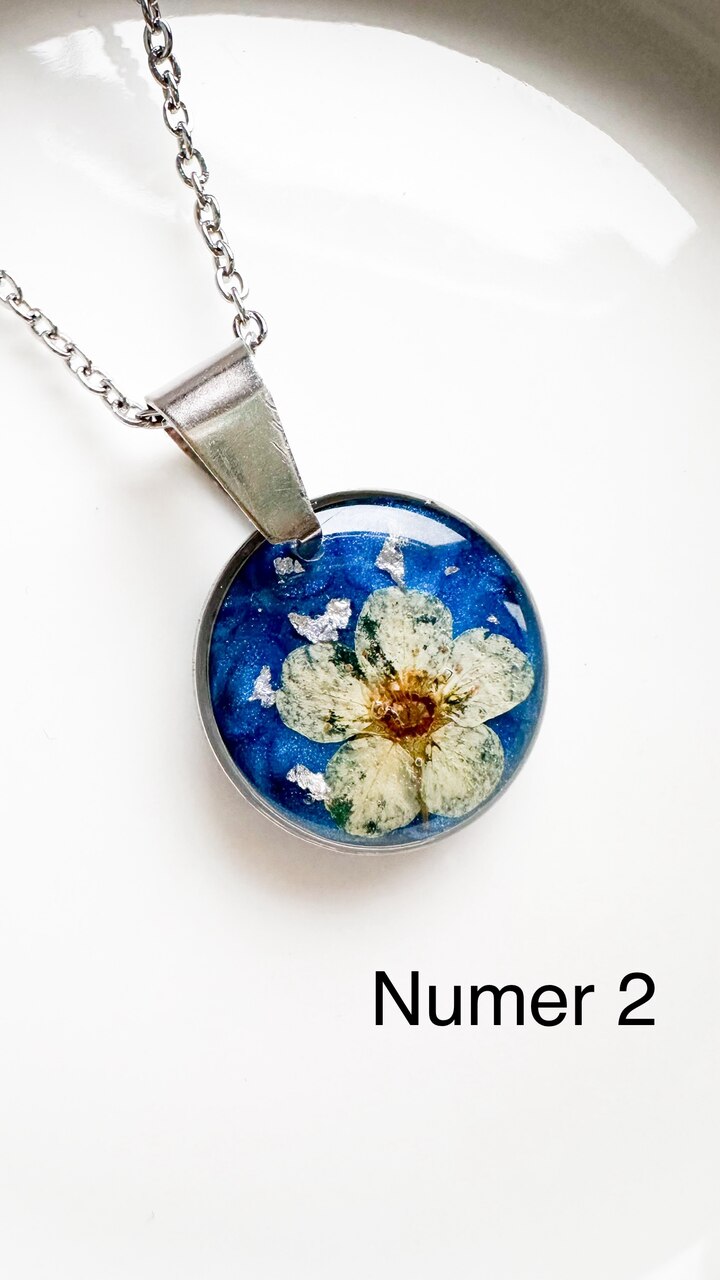 naszyjnik z kwiatów zalanych żywicą, biżuteria z prawdziwych kwiatów, biżuteria z żywicy epoksydowej, naszyjnik z żywicy z kwiatami, ręcznie robiona biżuteria z żywicy, biżuteria z suszonych kwiatów, nietypowy pomysł na prezent dla niej, biżuteria handmade, biżuteria z natury, prezent dla kobiety, unikalny prezent dla niej, naszyjnik z prawdziwymi kwiatami, naszyjnik z niebieskim tłem, naszyjnik szafirowy, biżuteria w kolorze kobaltowym, chabrowy naszyjnik z żywicy, delikatna biżuteria dla niej, ręcznie robiony naszyjnik z żywicy, biżuteria artystyczna, prezent z duszą, kwiaty zatopione w żywicy, biżuteria dla miłośniczki natury