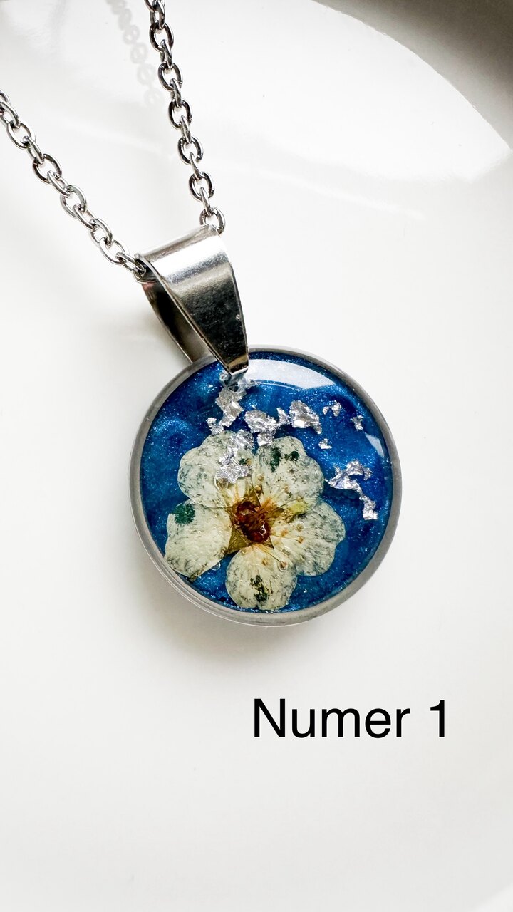 naszyjnik z kwiatów zalanych żywicą, biżuteria z prawdziwych kwiatów, biżuteria z żywicy epoksydowej, naszyjnik z żywicy z kwiatami, ręcznie robiona biżuteria z żywicy, biżuteria z suszonych kwiatów, nietypowy pomysł na prezent dla niej, biżuteria handmade, biżuteria z natury, prezent dla kobiety, unikalny prezent dla niej, naszyjnik z prawdziwymi kwiatami, naszyjnik z niebieskim tłem, naszyjnik szafirowy, biżuteria w kolorze kobaltowym, chabrowy naszyjnik z żywicy, delikatna biżuteria dla niej, ręcznie robiony naszyjnik z żywicy, biżuteria artystyczna, prezent z duszą, kwiaty zatopione w żywicy, biżuteria dla miłośniczki natury